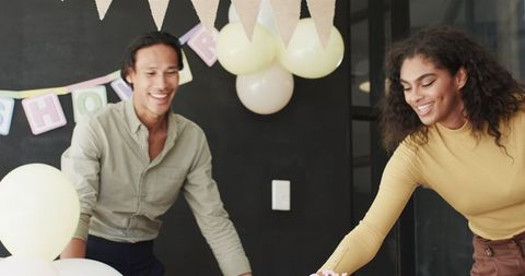 Multiracial colleagues decorating for party in office setting
