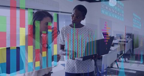 Businesswomen collaborating over laptop with data visualizations and analytics dashboards