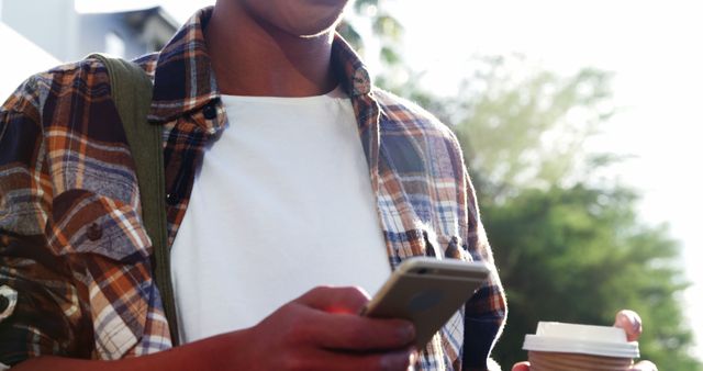 Young Adult Checking Smartphone and Holding Coffee Cup Outdoors - Download Free Stock Images Pikwizard.com