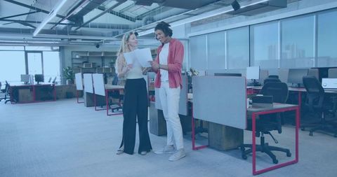 Colleagues reviewing documents in modern open-plan office, teamwork and collaboration