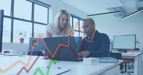 Colleagues Analyzing Data with Graphs in Modern Office