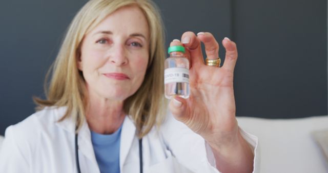 Female Doctor Smiling and Holding COVID-19 Vaccine Bottle - Download Free Stock Images Pikwizard.com