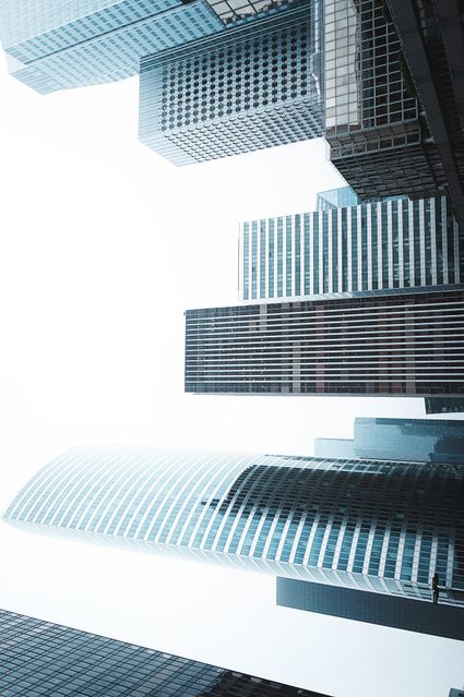 Interesting perspective of modern skyscrapers and office buildings with a bright white sky in the background. Ideal for corporate websites, business brochures, architecture portfolios, or urban development presentations. The clean aesthetic emphasizes modernity and professionalism, making it suitable for articles or content focused on growth and innovation in urban infrastructure.