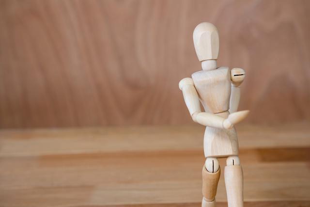 This image shows a wooden art mannequin in a walking pose on a wooden surface with a wooden background. It can be used for art and design projects, illustrating concepts of movement, creativity, and human figure studies. Ideal for educational materials, art tutorials, and creative design inspiration.