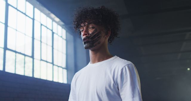 Young Man with Face Paint Standing in Warehouse - Download Free Stock Images Pikwizard.com