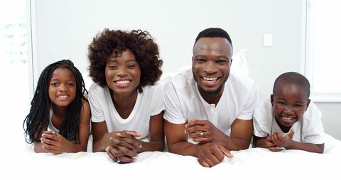 Happy Family Lying Together on Bed in Bright Bedroom