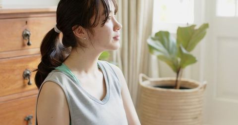 Asian Woman Reflecting in Cozy Home Interior with Natural Light