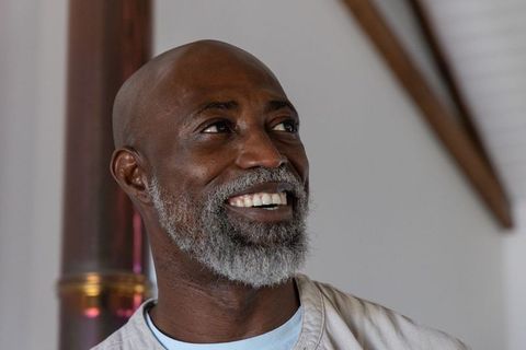 Warm senior african american man smiling, looking left indoors with gray beard