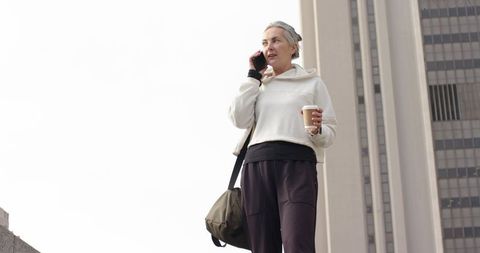 Senior Woman Talking on Phone Holding Coffee in Urban Plaza — Active City Lifestyle