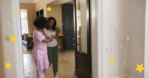 Home nurse checking patient wrist during in-home assessment with stethoscope in hallway