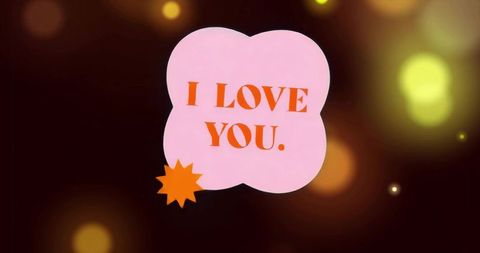 Floating pink speech bubble reading I LOVE YOU with orange starburst and bokeh lights