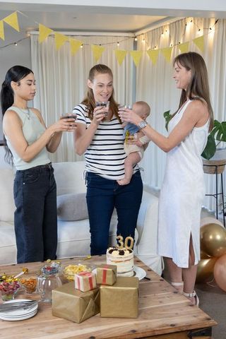 Women Celebrating a Birthday with Toast and Baby in Cozy Living Room