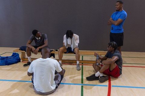 Multiracial basketball team resting and cooling down after intense court training