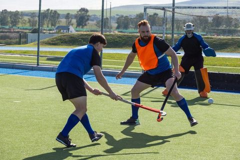 Male Field Hockey Players Practicing with Goalkeeper Outdoors