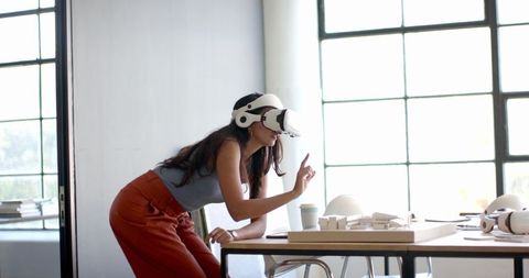 Woman Wearing VR Headset Interacting with Virtual Models in Office