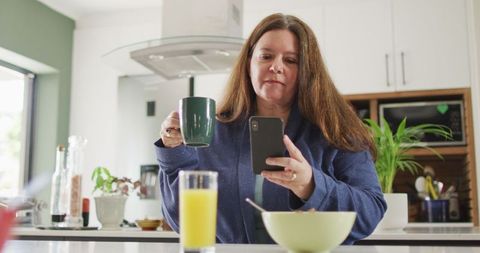 Woman Sharing Breakfast Experience with Smartphone in Kitchen