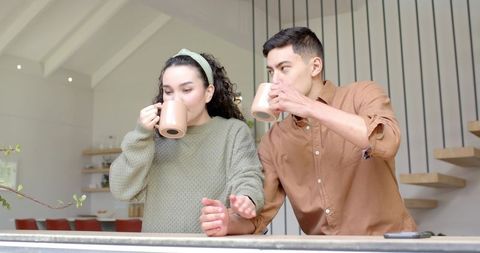Couple Relaxing with Ceramic Mugs in Modern Kitchen