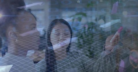 Collaborating women placing colorful sticky notes on glass with digital wireframe overlay
