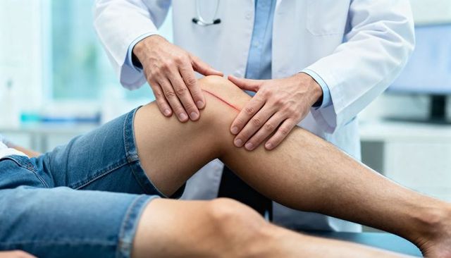 Doctor examining knee scar during orthopedic follow-up visit, clinical assessment