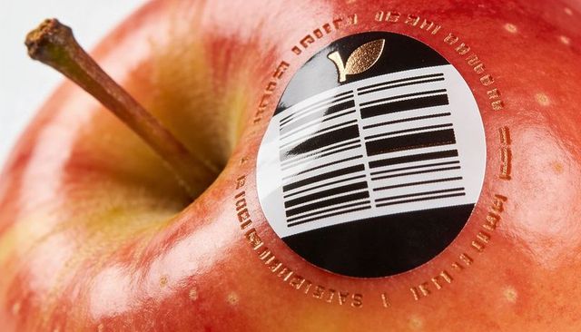 Closeup red apple displaying barcode sticker with gold-foiled microtext and glossy skin