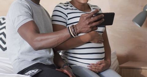 Expecting couple sharing ultrasound photos on smartphone
