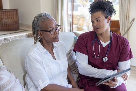 Young nurse discussing care plan with senior african american woman using tablet at home