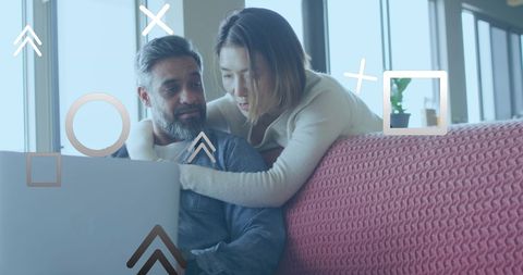 Couple planning vacation using laptop with digital overlay