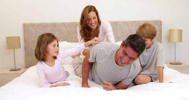 Happy Family Playfully Bonding on Bed in Cozy Home Interior - Download Free Stock Images Pikwizard.com