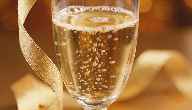 Sparkling champagne flute showing rising bubbles and gold ribbon for celebration