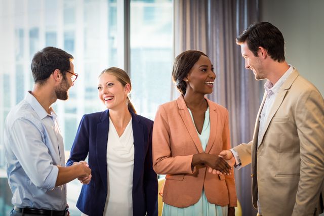 Business professionals shaking hands in modern office, symbolizing successful collaboration and partnership. Ideal for use in corporate websites, business presentations, and marketing materials to convey teamwork, diversity, and professional relationships.