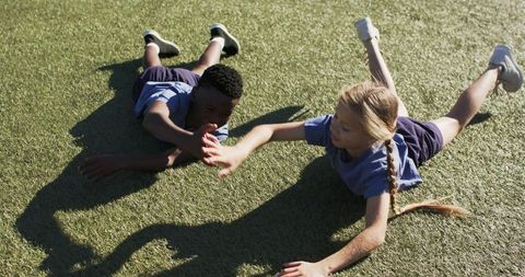 Playing together on turf: diverse children reaching hands, teamwork and active outdoor play
