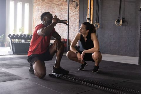 Diverse fitness partners pausing to hydrate after battle rope workout