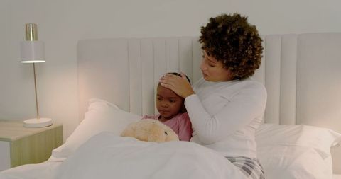 Mother Caring for Sick Child in Cozy Bedroom Evening