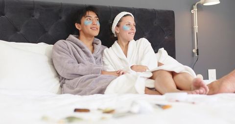 Diverse couple enjoying at-home spa night wearing under-eye patches and plush robes