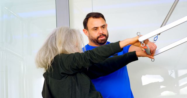 A therapist assists a senior woman in physical rehabilitation exercises, demonstrating a hands-on approach to physical therapy. This image can be useful for depicting healthcare services, elderly care programs, rehabilitation centers, and medical support services. Ideal for illustrating physical therapy routines and the importance of guided exercise for senior citizens.