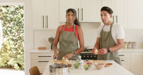 African American Couple Preparing Fresh Fruit at Kitchen Island Wearing Olive Aprons