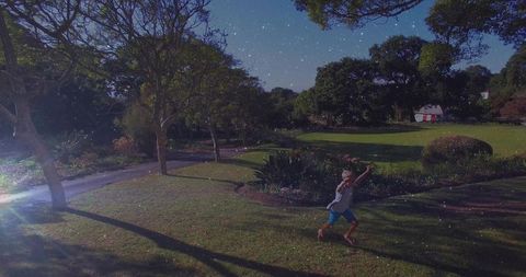 Child walks barefoot in park under starry evening sky