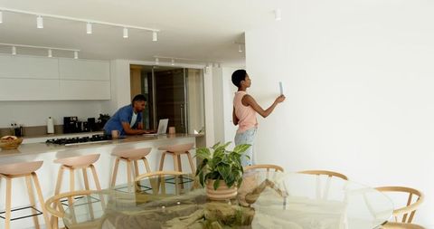 Couple collaborating in modern kitchen with color samples and laptops
