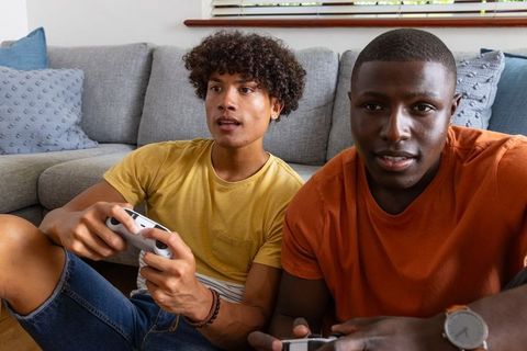 Young diverse friends playing video games on couch during casual competitive gaming night