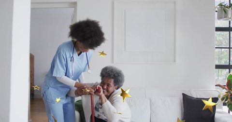 Home nurse assisting senior woman with cane on sofa in bright living room with golden stars