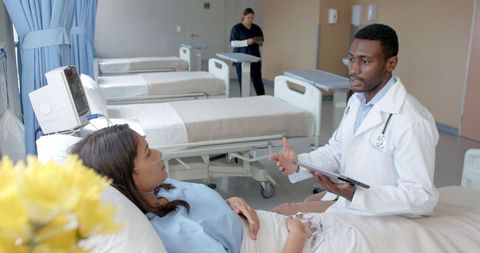 Doctor Consults Patient in Hospital Ward