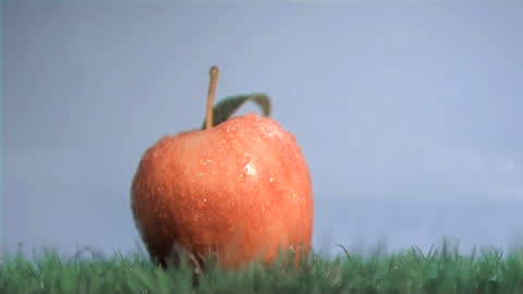 Red Apple in Slow Motion Under Raindrops and Blue Sky