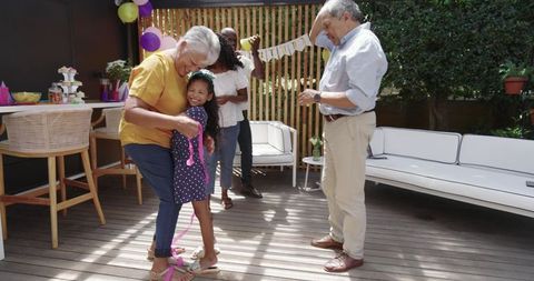Grandmother Hugging Joyful Granddaughter at Multigenerational Backyard Celebration