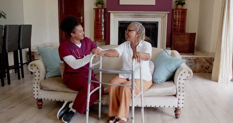 African American Caregiver Assisting Senior Woman in Living Room