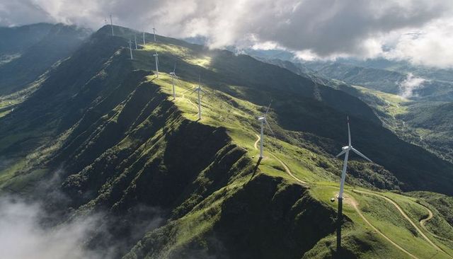 Wind turbines lining mountain ridge with winding service road