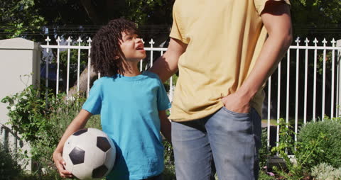 Father and Son Bonding with Soccer Ball in Garden