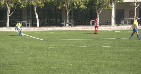 Youth Soccer Team Free Kick in School Field Under Sunny Sky