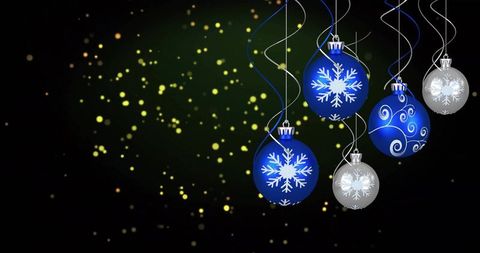 Hanging blue and silver snowflake ornaments with warm bokeh and left-side copy space