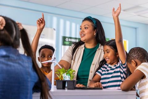 Teacher guiding diverse elementary students building wind turbine and plant stem project