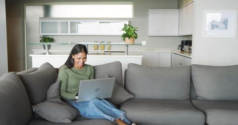 Smiling Woman Working on Laptop at Modern Home Lounge Area